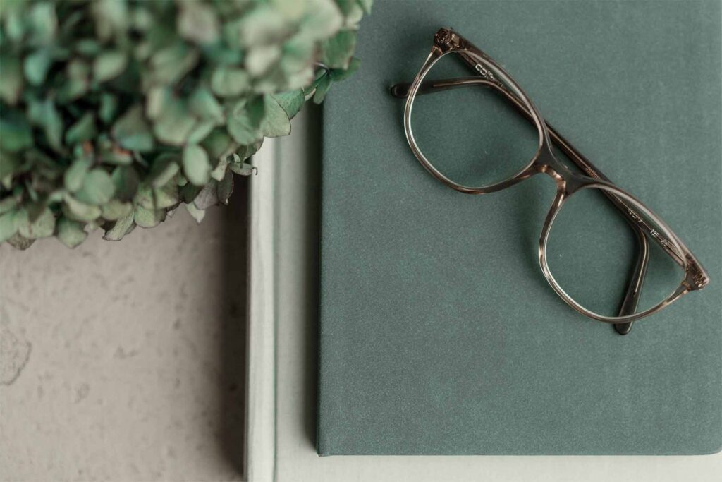 Was ist Achtsamkeit/ Mindfulness?: grüne gestapelte Bücher mit abgelegter Brille.
