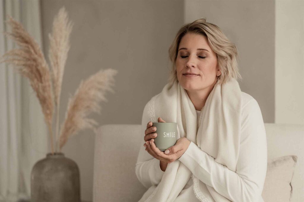 Was ist Achtsamkeit/ Mindfulness?: Julia Jäger hält eine Tasse Tee in den Händen und spürt die Wärme des Bechers mit geschlossenen Augen