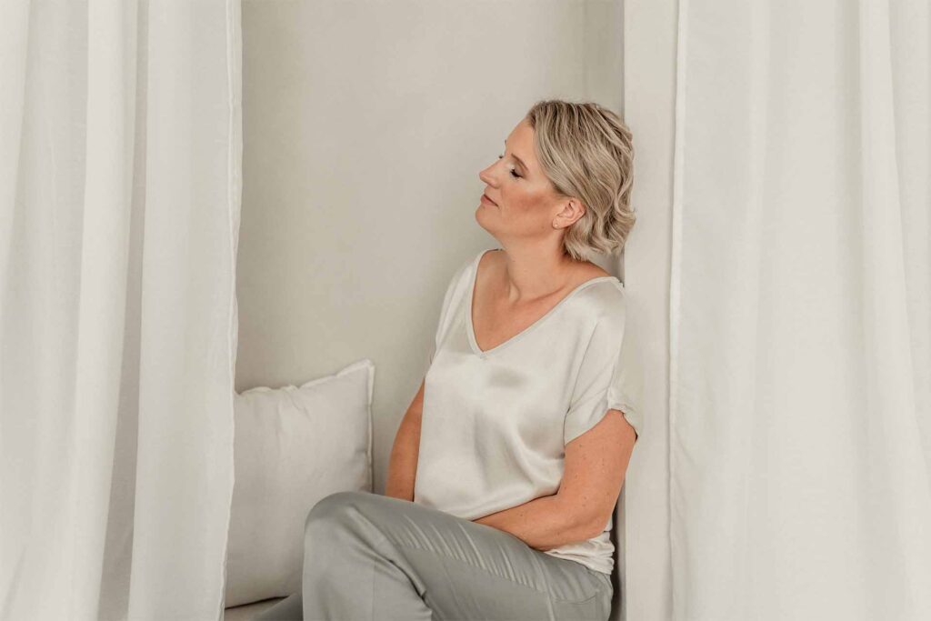 Me-Time finden im Alltag: Julia Jäger lehnt sitzend mit geschlossenen Augen an einer Wand